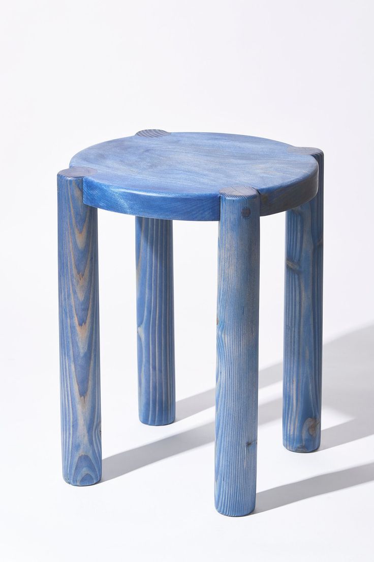 a small blue stool sitting on top of a white floor next to a wooden table