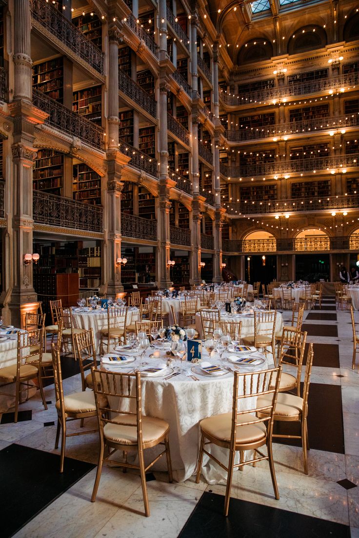 tables and chairs set up in the middle of a large room with many bookshelves