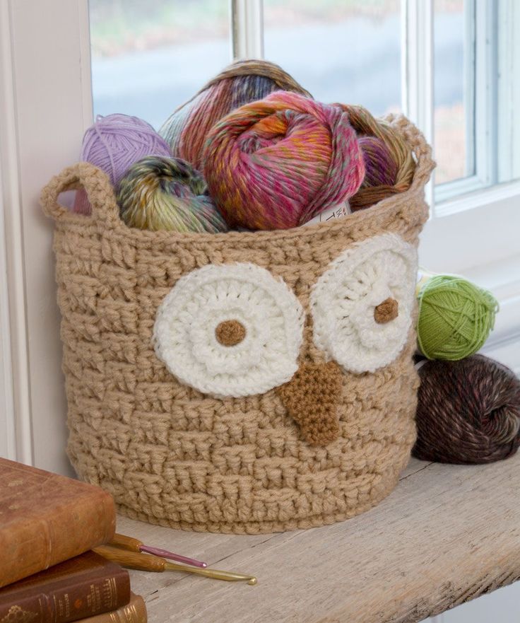 a crocheted owl basket with balls of yarn in it