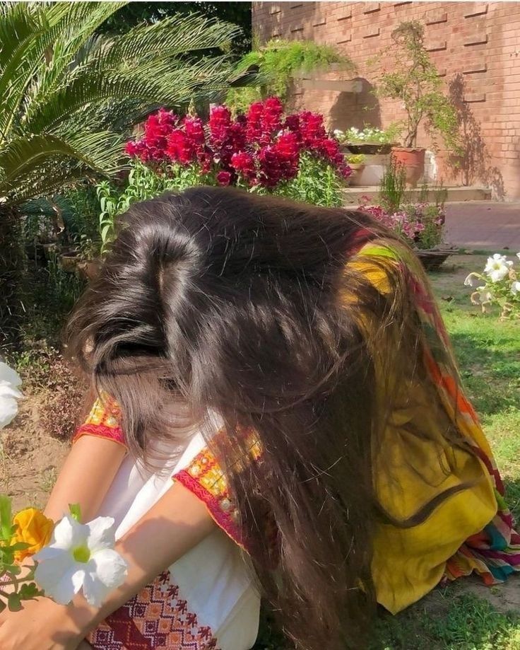 a woman sitting on the ground next to flowers