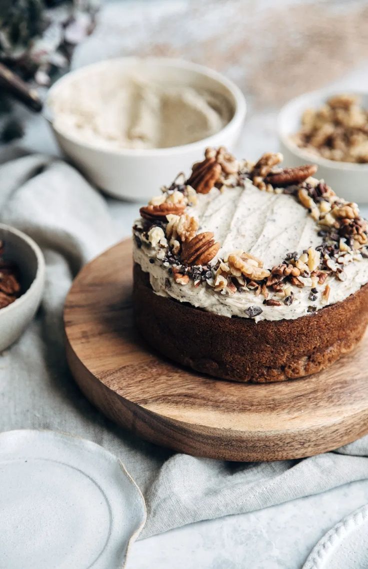 a cake on a wooden platter with nuts and cream