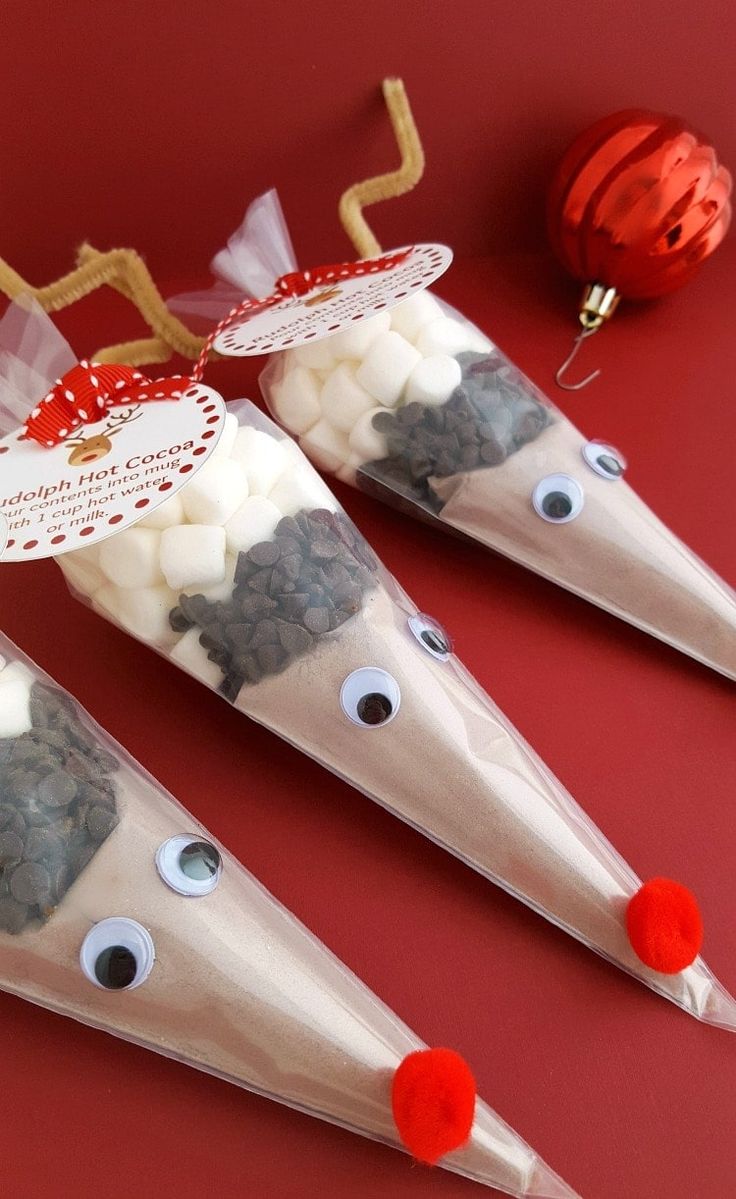 three plastic cones with eyes and noses on top of a red surface next to a christmas ornament