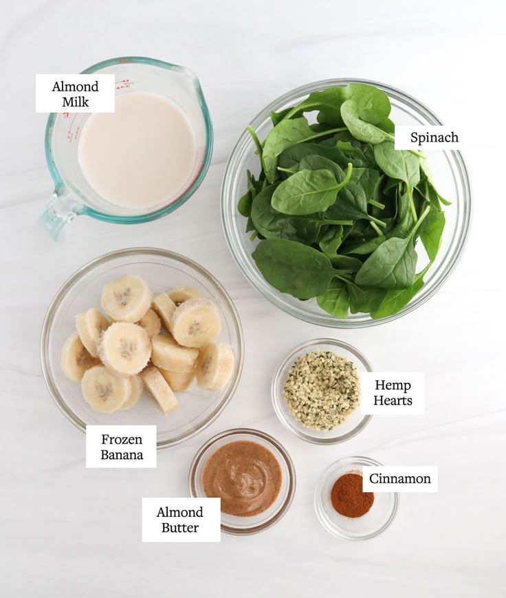 ingredients to make spinach and banana smoothie laid out on a white counter top