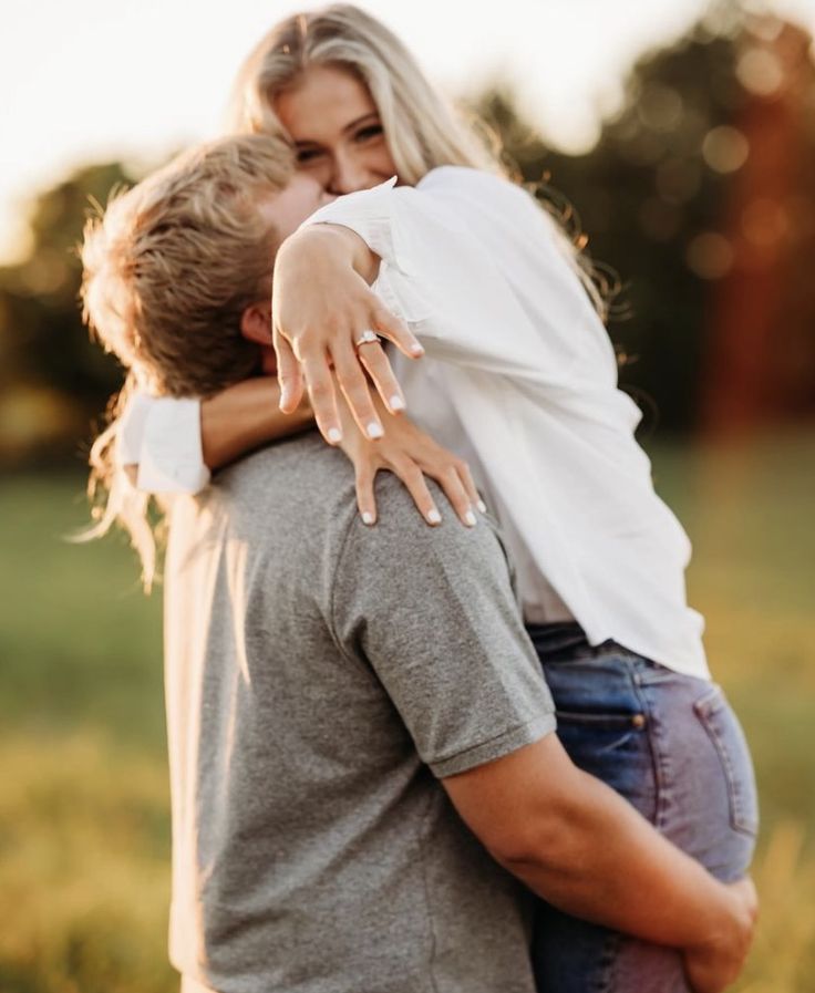 a man and woman hugging each other in the grass