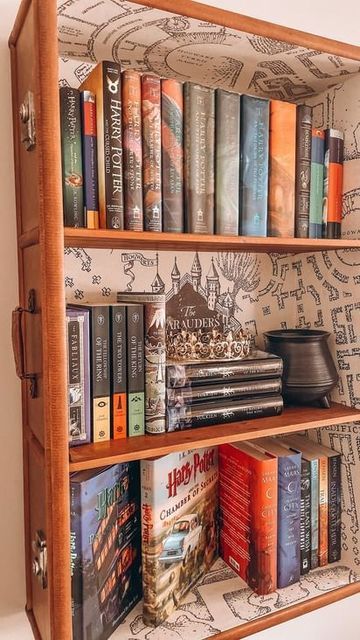 a wooden book case filled with books on top of a white wall covered in maps