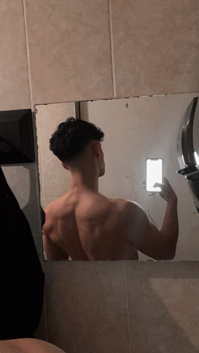 a shirtless man is looking in the mirror