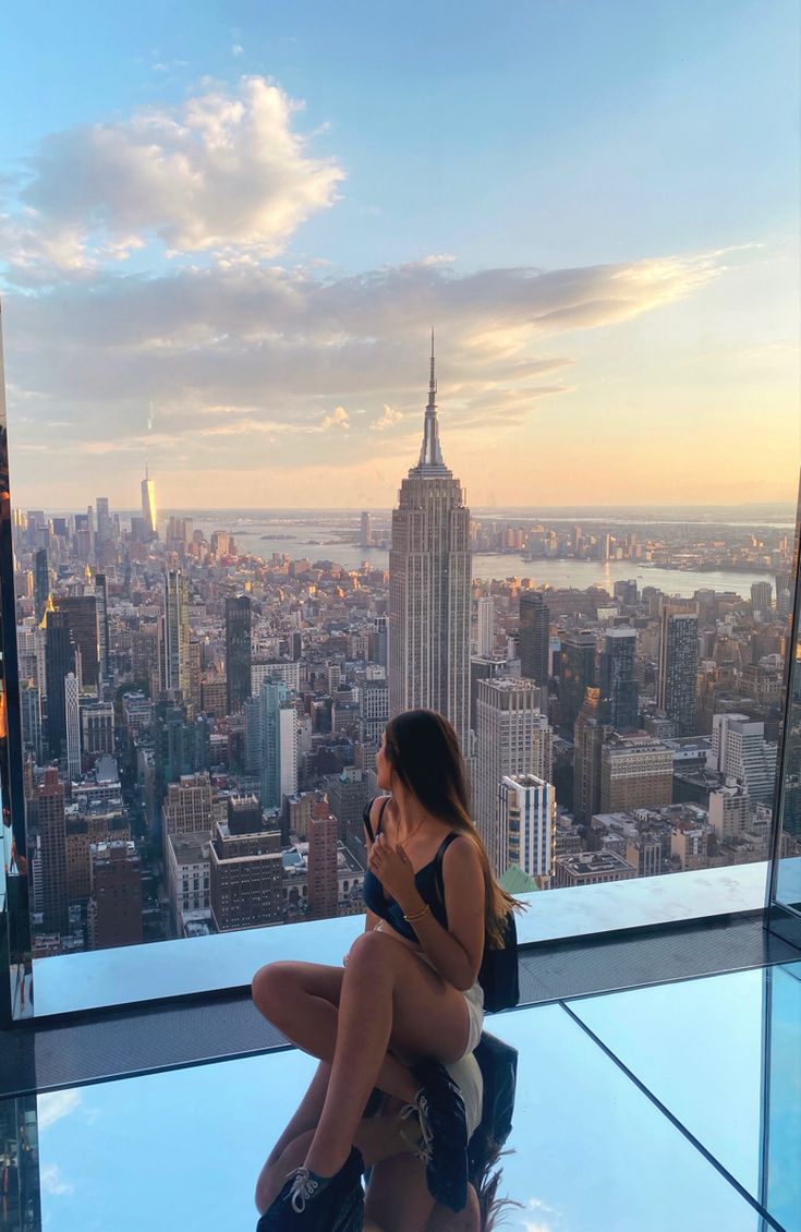 a woman sitting on top of a building looking at her cell phone in the city