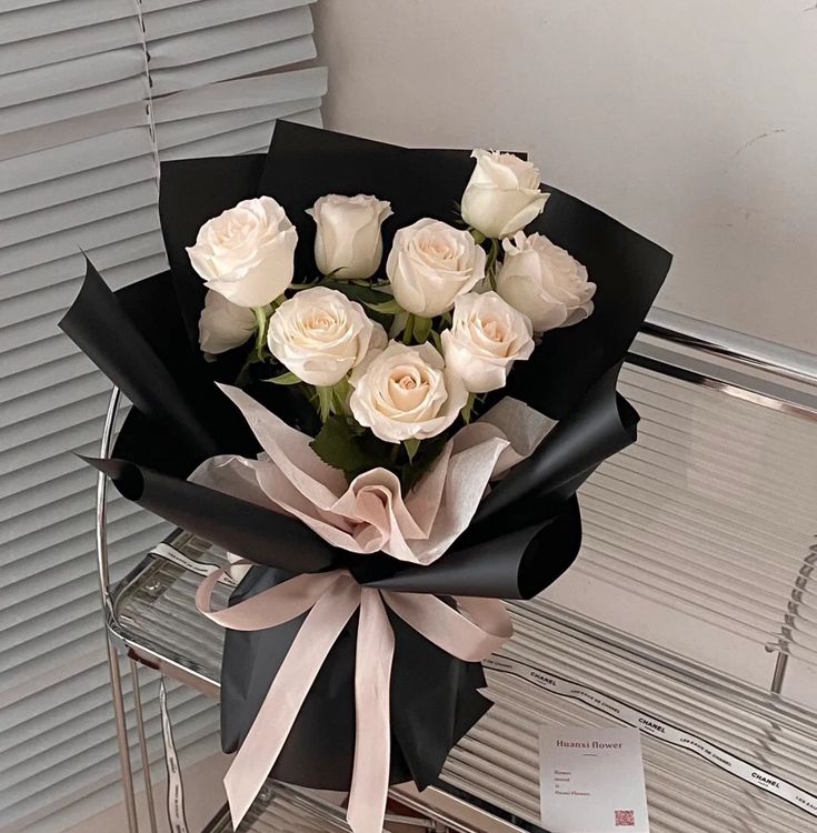 a bouquet of white roses sitting on top of a glass table next to a card