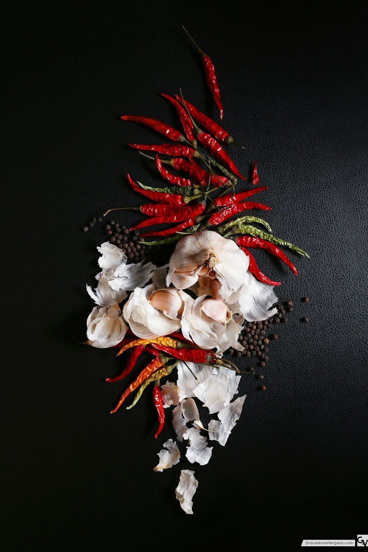 white flowers and red peppers on a black surface