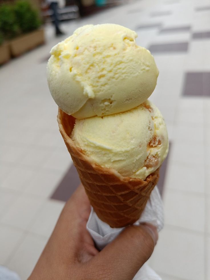 two scoops of ice cream on top of each other in someone's hand