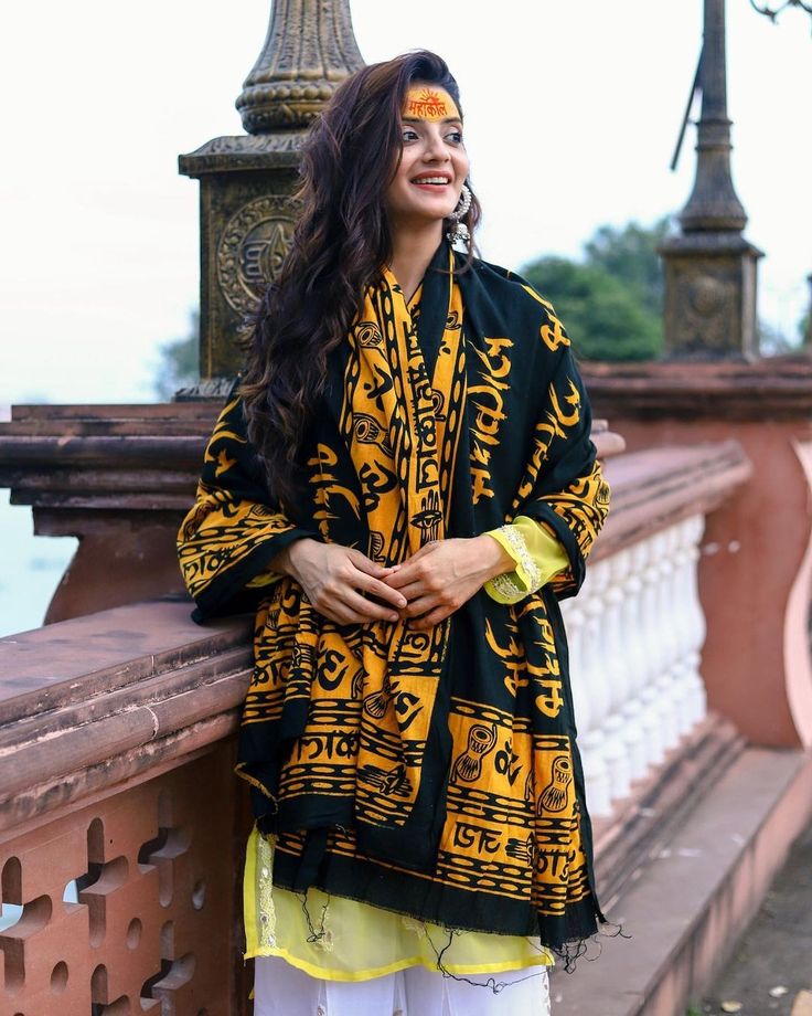 a woman standing next to a wall wearing a yellow and black jacket