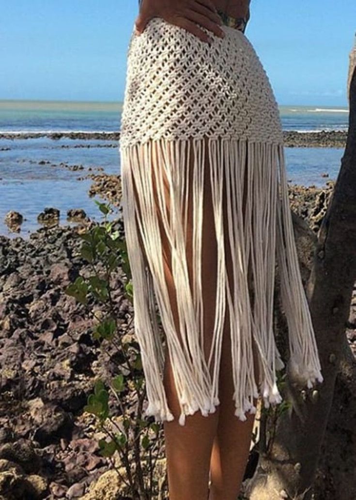 a woman in a white skirt standing next to the ocean