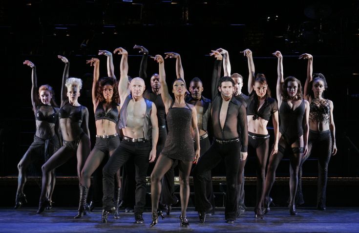 a group of dancers posing for a photo on stage with their arms in the air