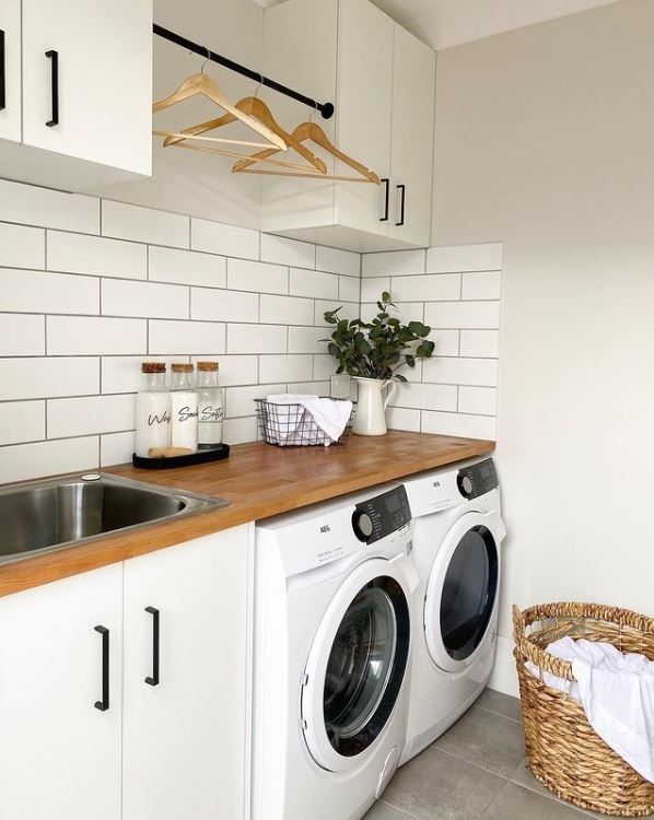 a washer and dryer sitting in a kitchen next to a counter with a basket on it