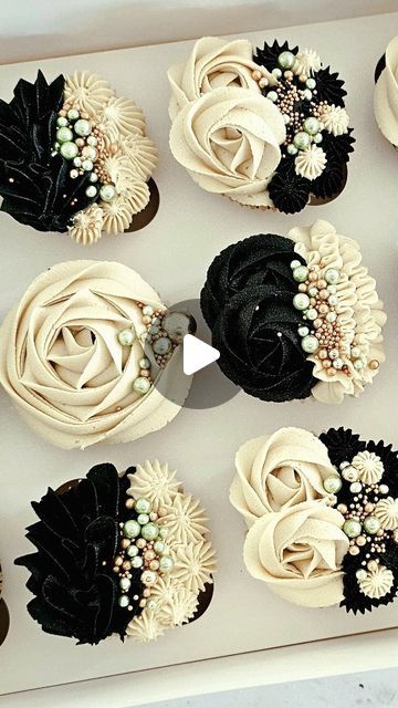 cupcakes decorated with black and white flowers in a box