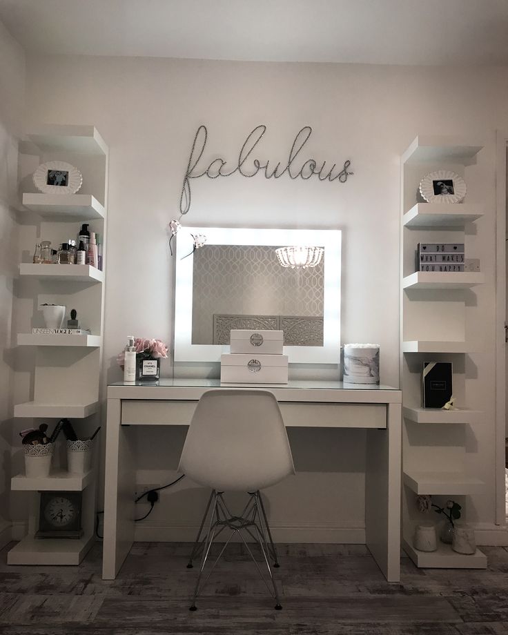 a white desk with a laptop on top of it in front of a mirror and shelves