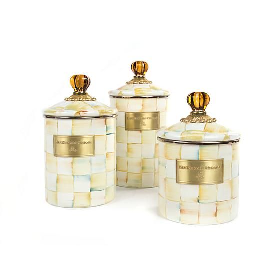 three white and gold canisters with lids