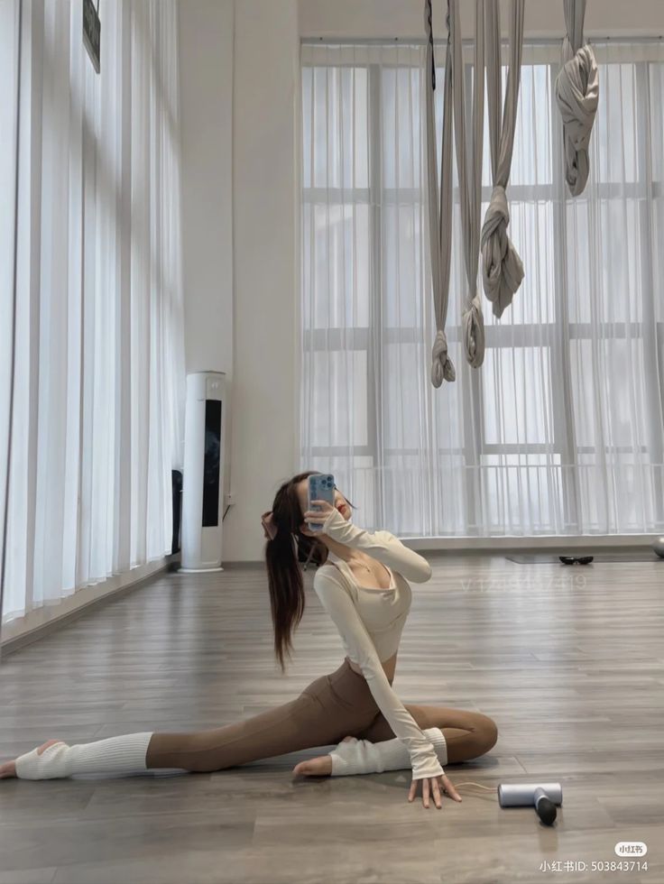 a woman sitting on the floor with her legs crossed and headphones hanging in front of her