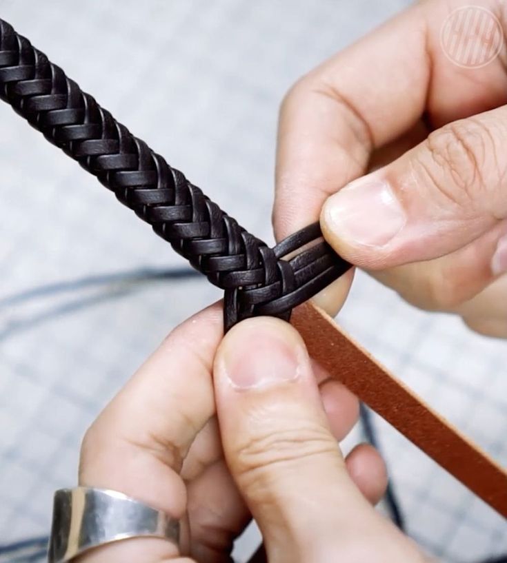 a person is working on a piece of braiding with wood and metal wire in their hands