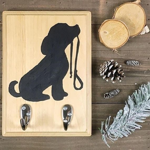 a wooden plaque with a black dog on it next to pine cones and other decorations