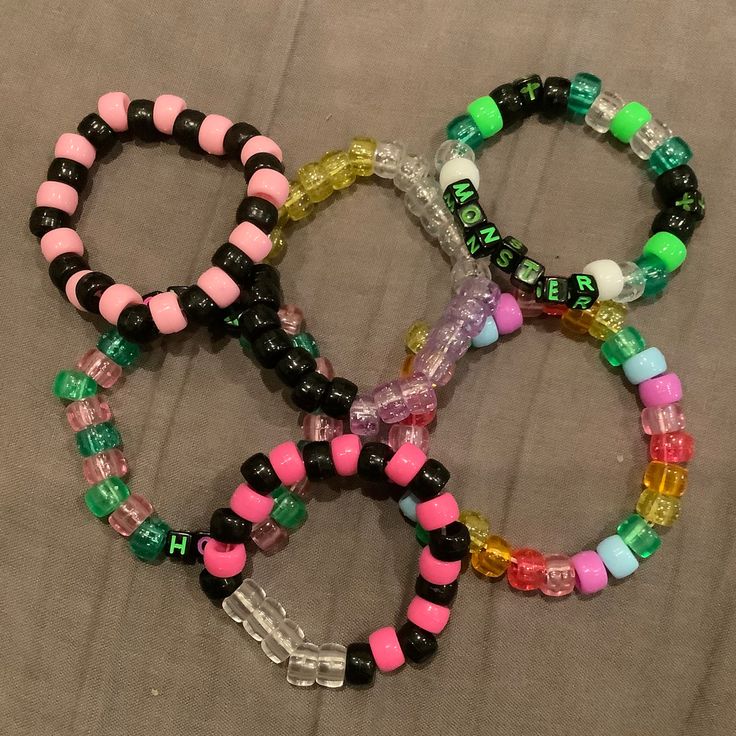 four bracelets with different colors and designs on them sitting next to each other in a pile