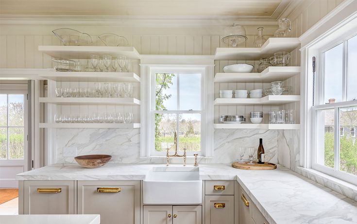 a kitchen with marble counter tops and open shelving above the sink in front of a window