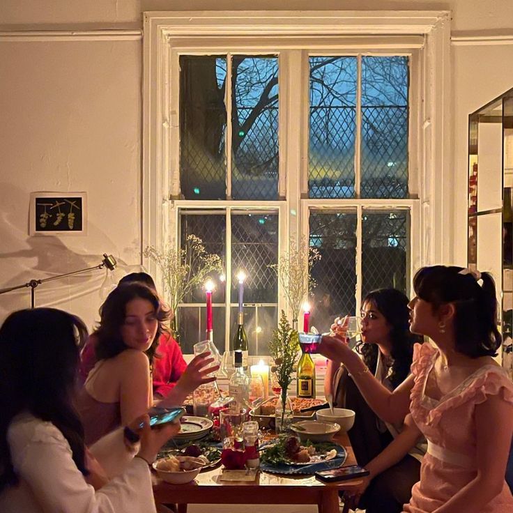 a group of women sitting around a table with food and candles in front of them