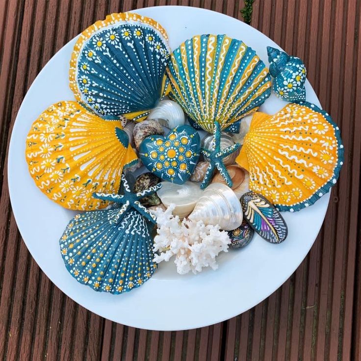 there are many seashells on the plate and one is painted blue, yellow and white