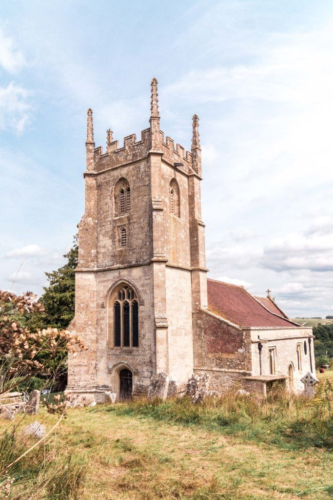 an old stone church with a tower on the side and grass in front of it