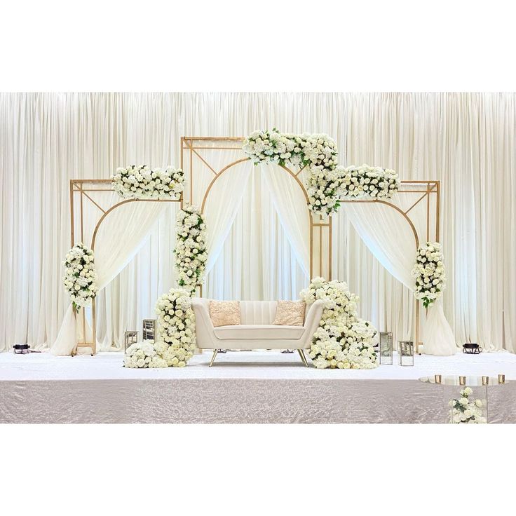 a wedding ceremony setup with white flowers and greenery on the side of the stage