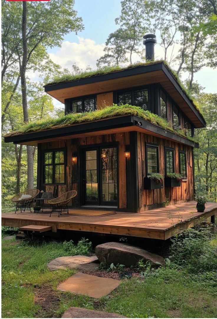 a small cabin in the woods with grass on top