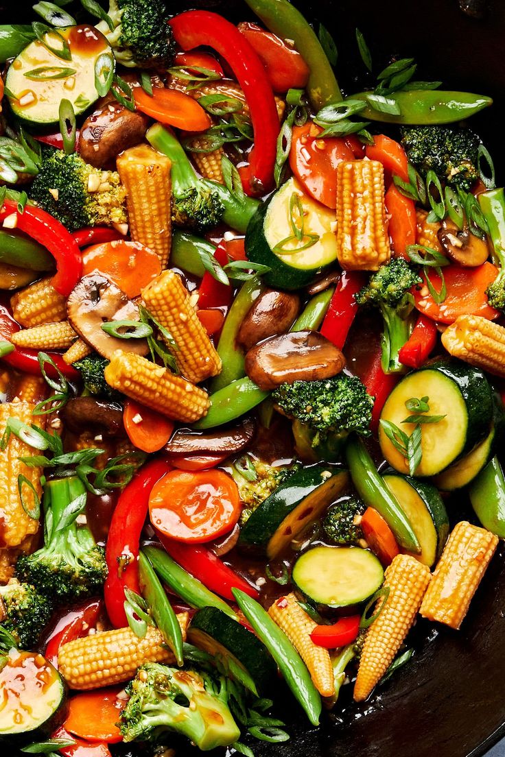 a skillet filled with vegetables and corn on the cob