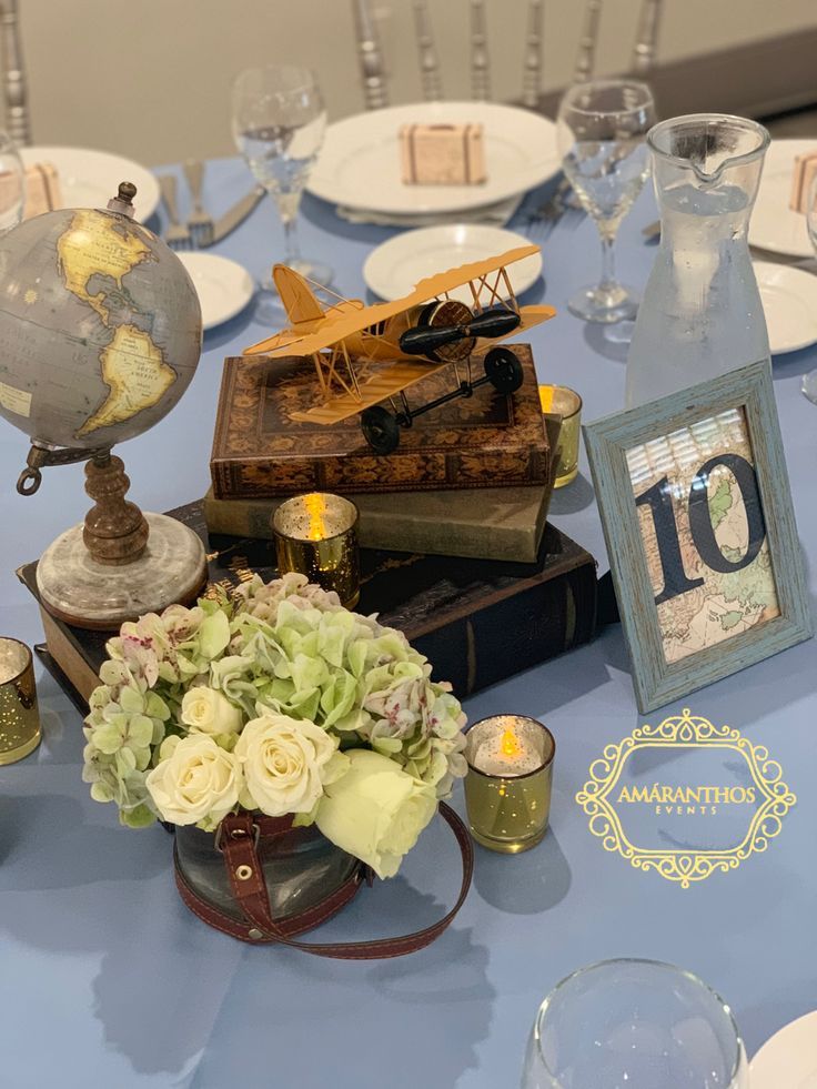 a blue table topped with lots of books and vases filled with flowers on top of it