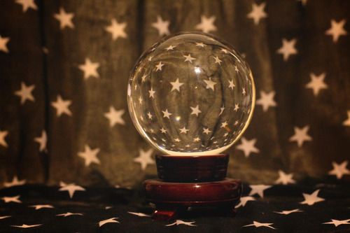 a snow globe sitting on top of a wooden stand in front of a curtained background