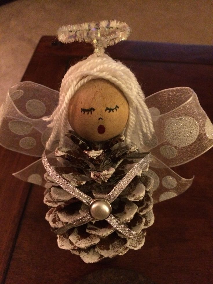 a pine cone angel ornament on top of a table