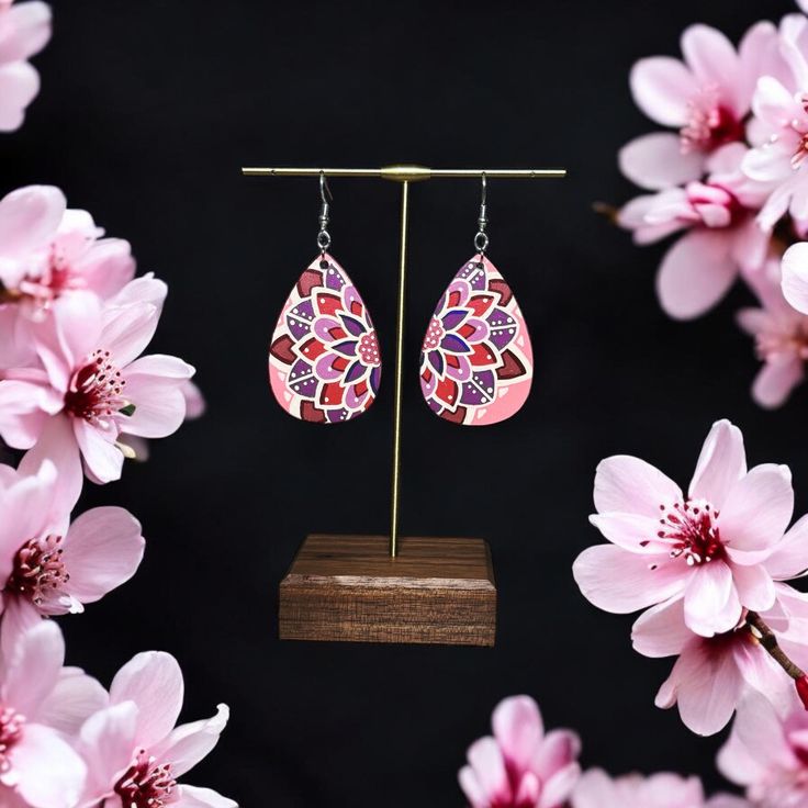 These bright and fun earrings feature a hand-painted mandala in shades of pink, purple, and maroon. Perfect for adding a vibrant touch of art to your look, they are ideal for when you want to make a bold statement. Earrings are hand painted on teardrop shaped , lightweight wood (2x1.5in.), and sealed with a non-toxic satin finish. The earring hooks are hypoallergenic stainless steel. Purple Hand Painted Bohemian Earrings, Bohemian Hand Painted Purple Earrings, Pink Bohemian Hand Painted Jewelry, Pink Artsy Jewelry For Festivals, Pink Colorful Jewelry As A Gift, Artsy Pink Jewelry For Festivals, Pink Jewelry For Gift, Artsy Pink Festival Jewelry, Pink Teardrop Jewelry For Festivals