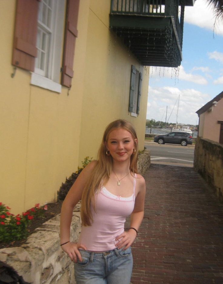 a woman is standing in front of a yellow building and posing for the camera with her hands on her hips