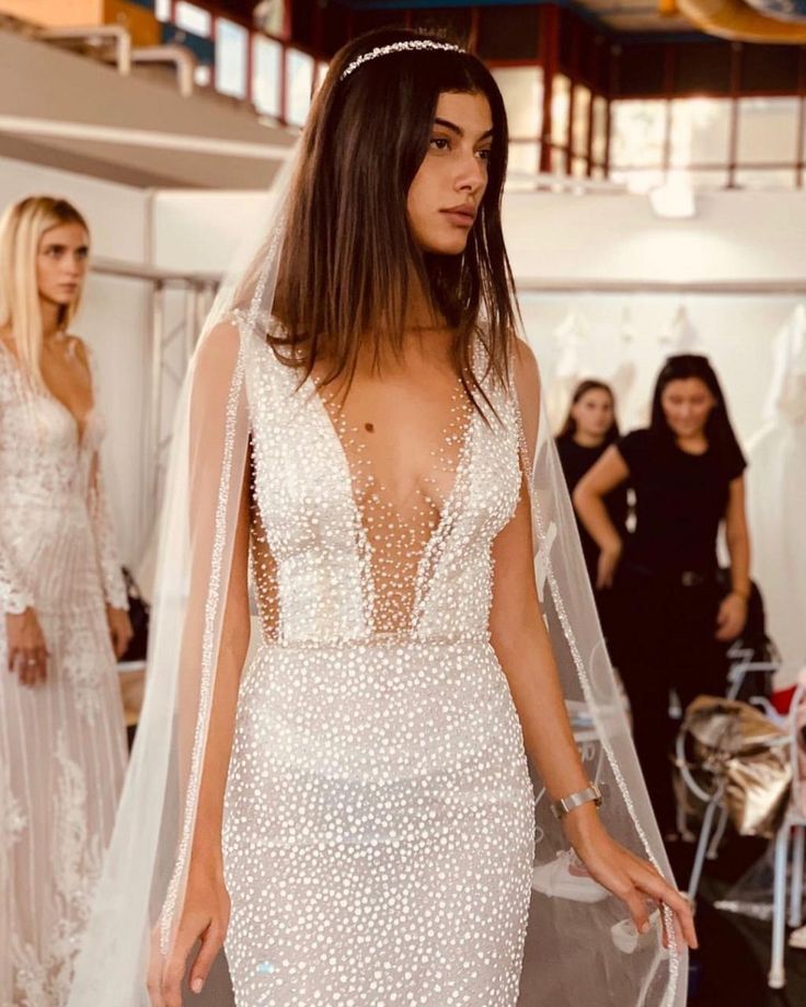 a woman in a wedding dress is walking down the runway with other women behind her