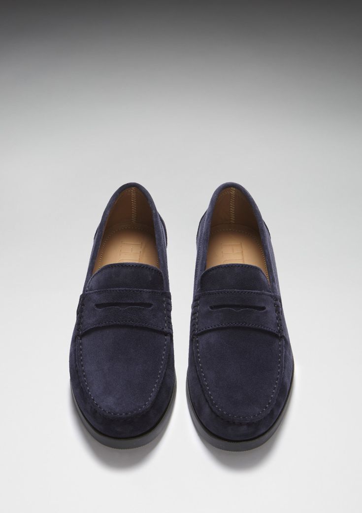 Here we offer you another Hugs & Co. take on a classic style. Our penny loafer upper made with carefully selected blue Italian suede is teamed with a robust boat shoe sole in slate grey rubber. This gives the shoes great wearability, fantastic comfort and the timeless style you're looking for in a penny loafer. We also offer loafers with tassels and driving shoes here at the Hugs & Co. online store. Our men's shoes are super cool and made to the tip top highest standards with leathers and suedes from England and Italy. If you're after preppy shoes or men's moccasins then you've come to the right place. UK Sizing Made in Portugal 100% Suede Upper featuring a 100% Leather Lining Rubber studded sole Blue Suede Loafers With Suede Lining, Classic Blue Suede Leather Shoes, Navy Suede Loafers For Formal Occasions, Navy Suede Slip-on Loafers, Navy Suede Loafers With Rubber Sole, Classic Navy Loafers With Leather Sole, Classic Blue Suede Slip-ons, Blue Suede Dress Shoes For Work, Blue Classic Boat Shoes For Formal Occasions