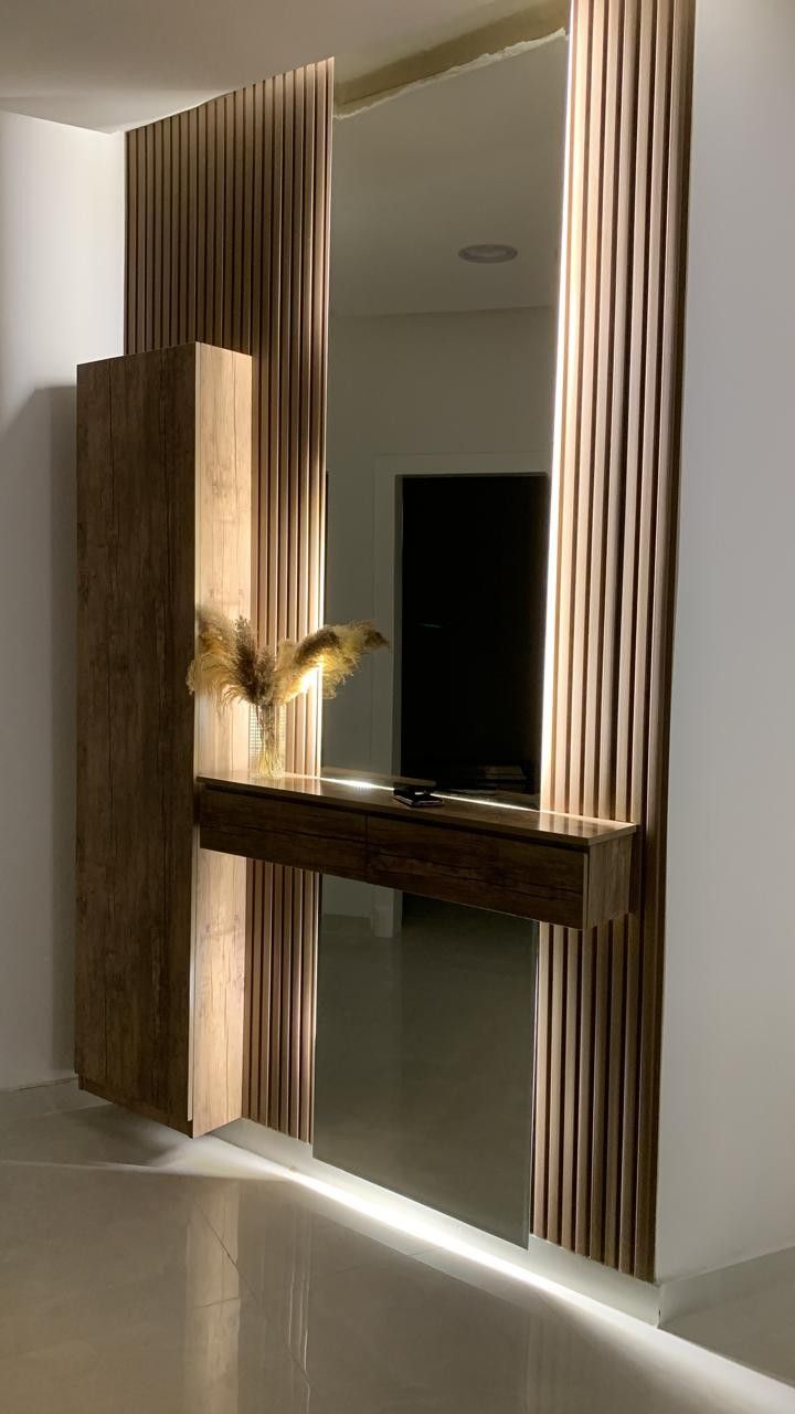 a large mirror sitting on the side of a wall next to a wooden shelf with flowers in it