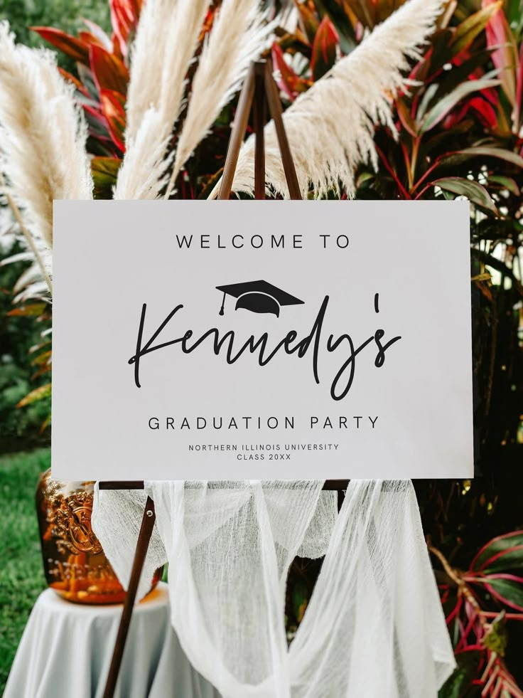 a sign that says welcome to kennely's graduation party in front of some plants