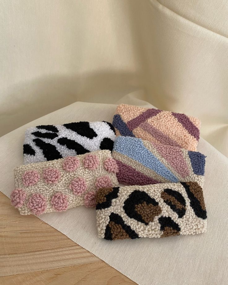 four pieces of knitted animal print fabric on a white cloth covered table with wood flooring