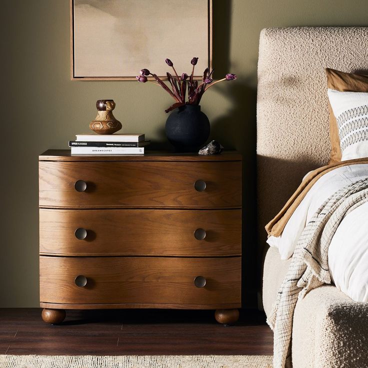 a bedroom scene with focus on the dresser and bed side table in the foreground