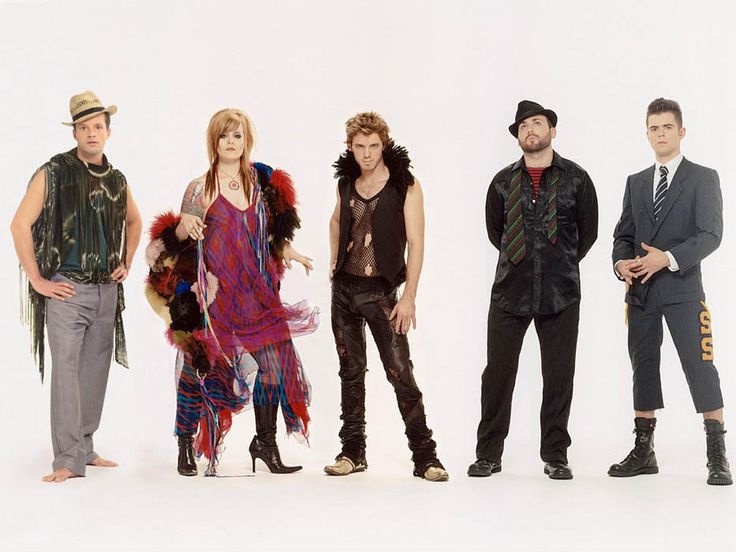 four people standing in front of a white background wearing clothes and hats with feathers on them