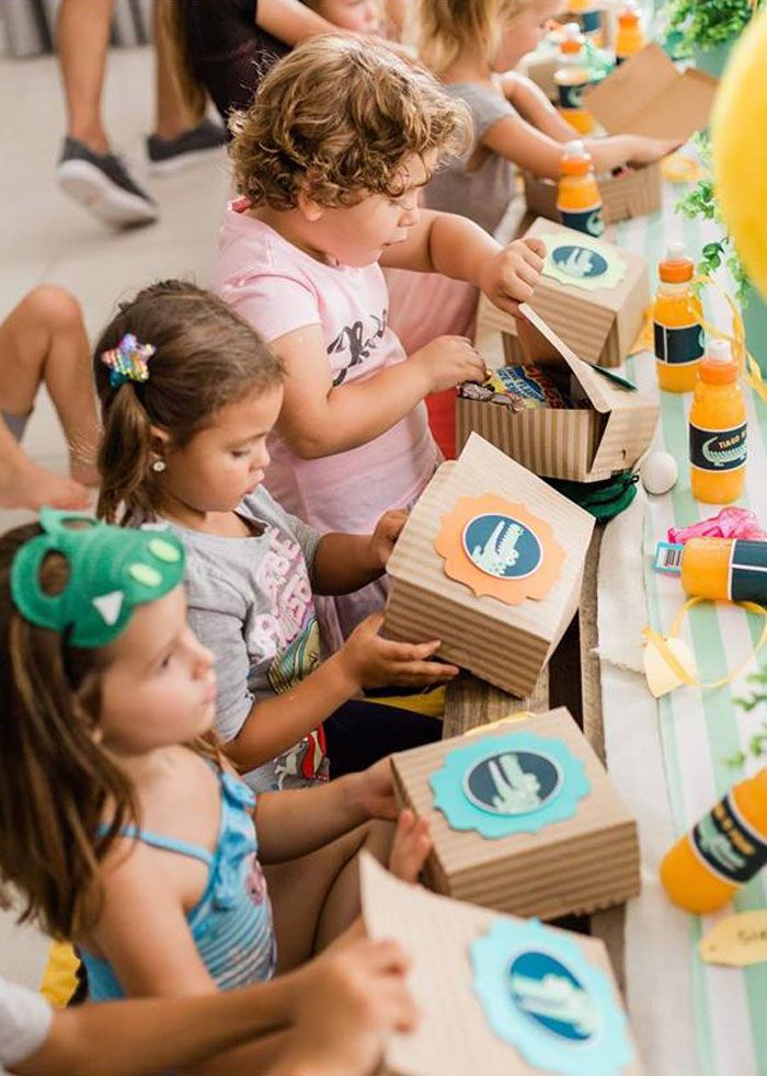 children sitting at a table with boxes and balloons