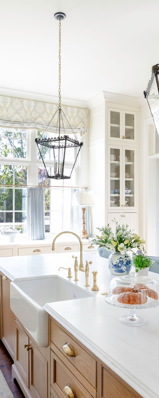 a kitchen with white counter tops and wooden cabinetry in the center, along with an island style sink