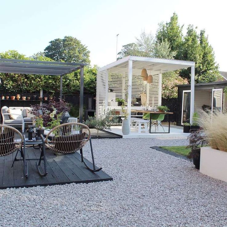 an outdoor patio with chairs and tables in the middle of it, surrounded by gravel