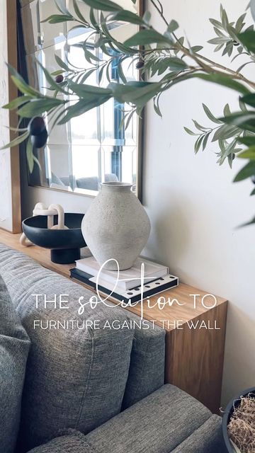 a living room with a couch, mirror and potted plant on the side table