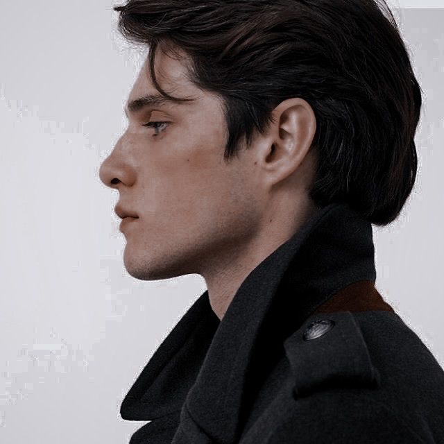 a man in a pea coat looking off into the distance with his head tilted to the side