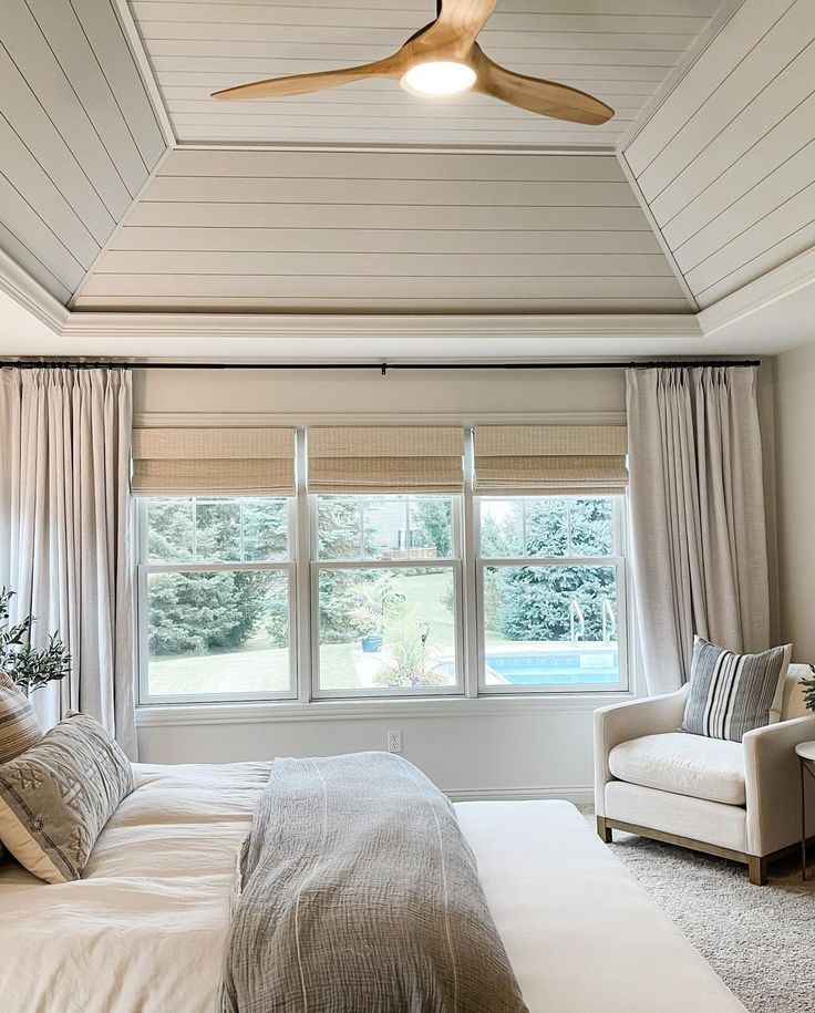 a bed room with a neatly made bed and a ceiling fan